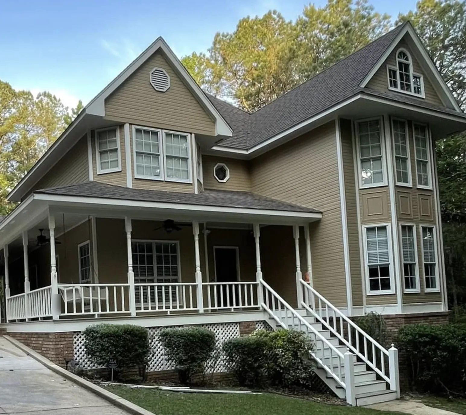 Two-story home with tan siding and white trim after exterior painting