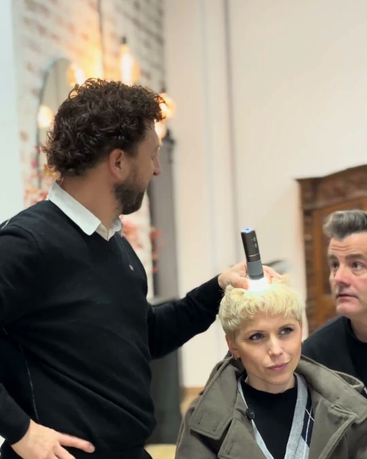 Manuel Peña revisando el cabello de una clienta durante un diagnóstico en el salón