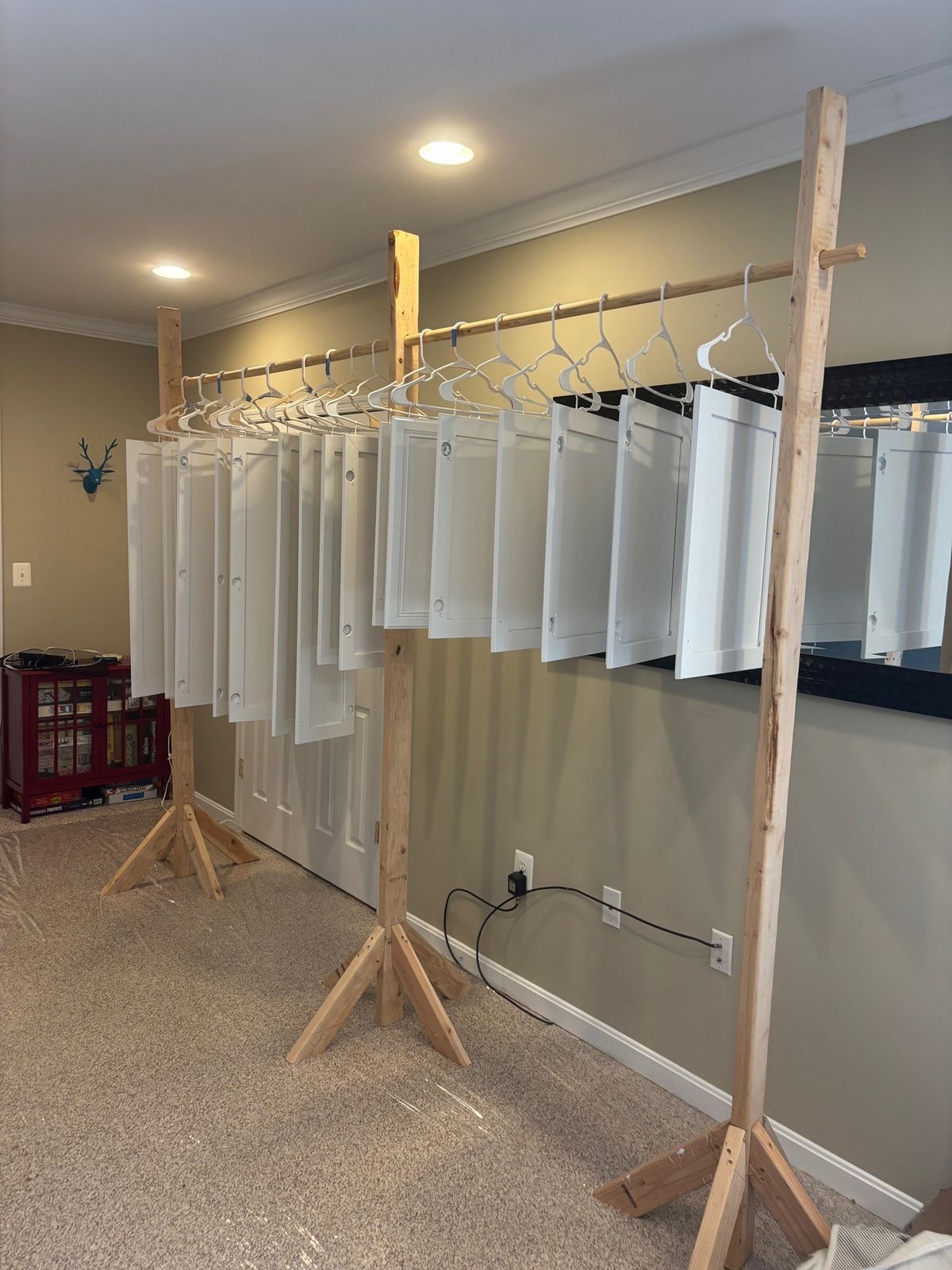 Freshly painted cabinet doors drying on a homemade rack during a kitchen repaint