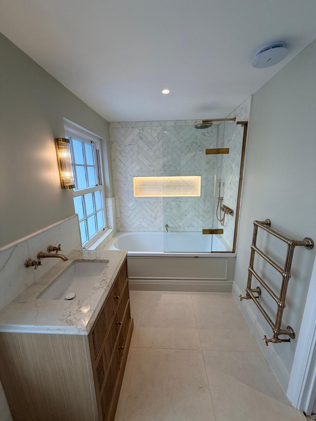 Bathroom by Novo Plumbing with herringbone tiles, an oak vanity and brushed brass fittings