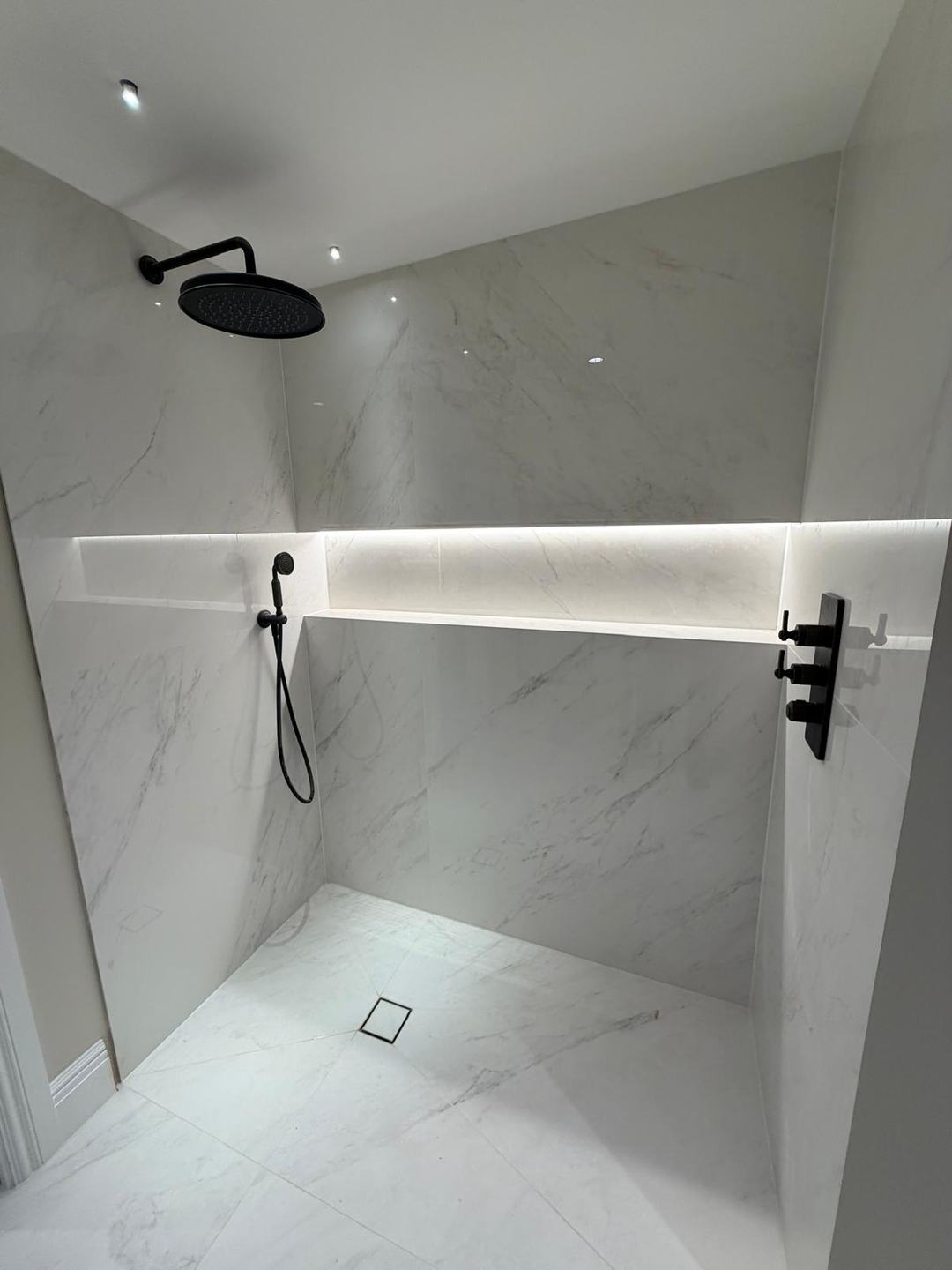 Walk-in wet room shower by Novo Plumbing with a lit alcove and matt black fittings