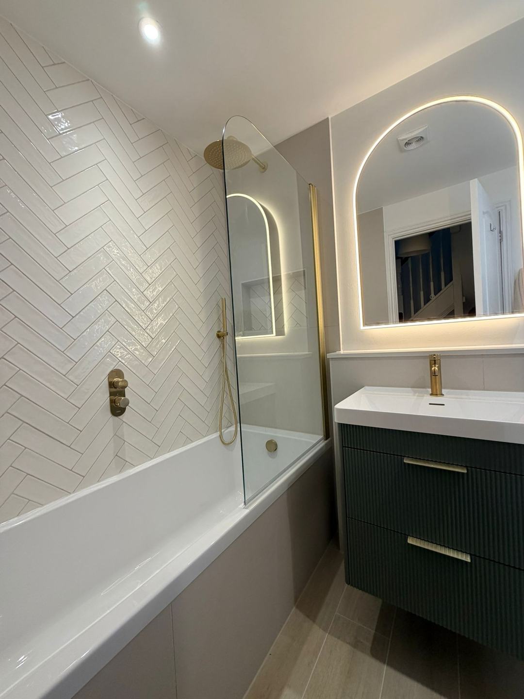 Bathroom refit by Novo Plumbing with herringbone tiles and an arched mirror