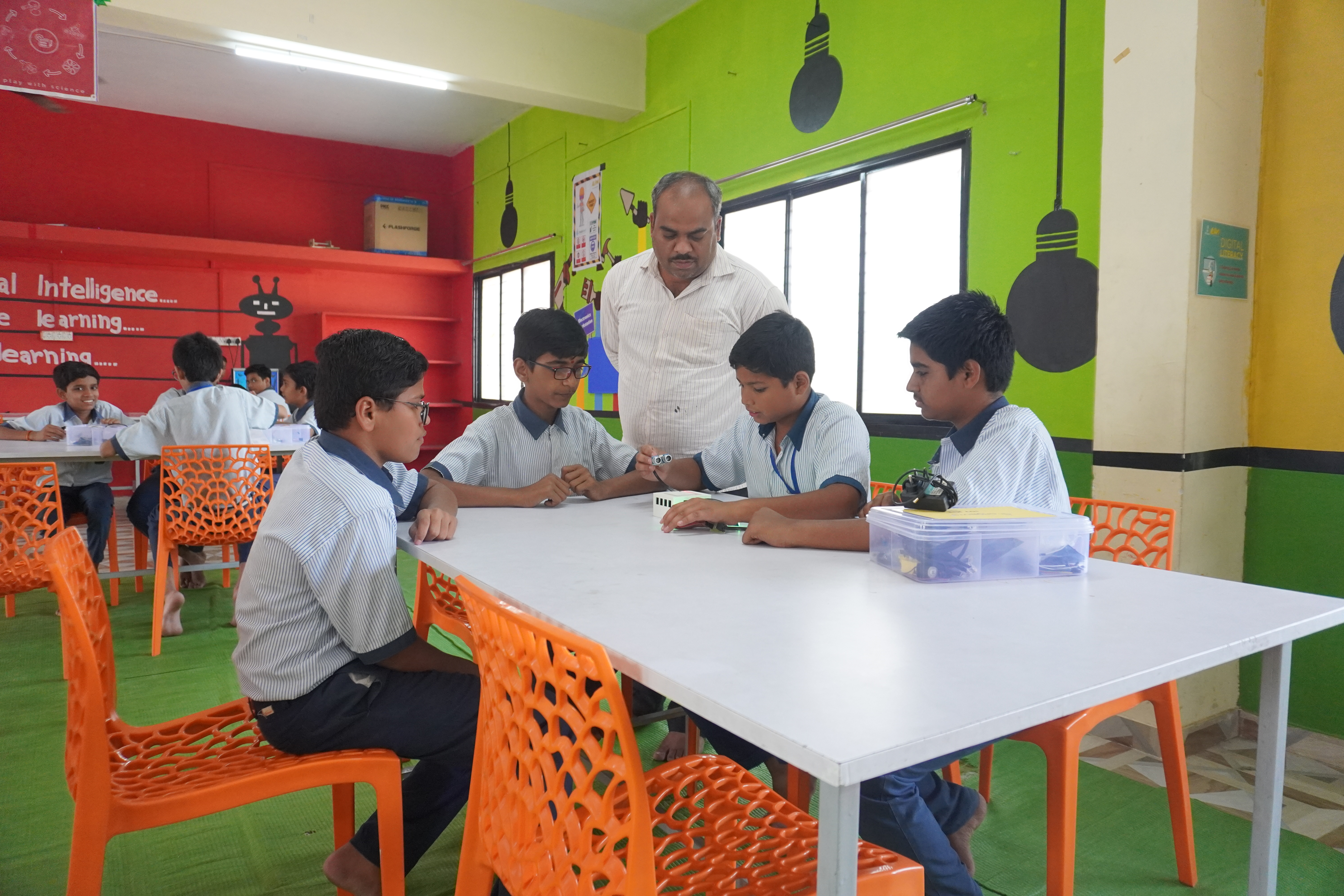 A Grobots resident trainer guiding students through a robotics activity in a school lab