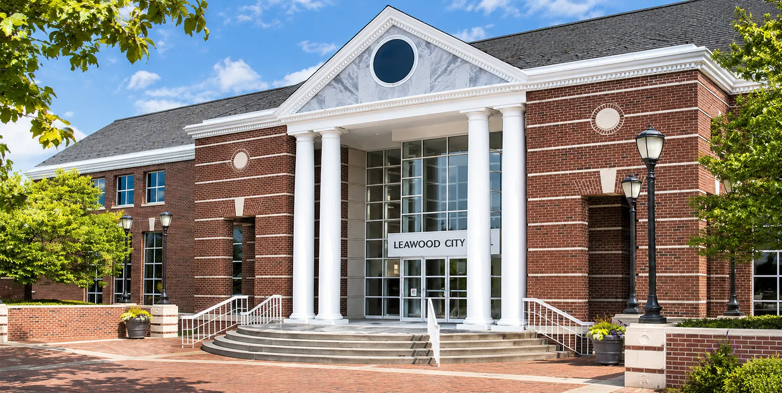 Illustration of Leawood City Hall in Leawood, Kansas, showing its red-brick exterior, white columns, and central glass entrance.