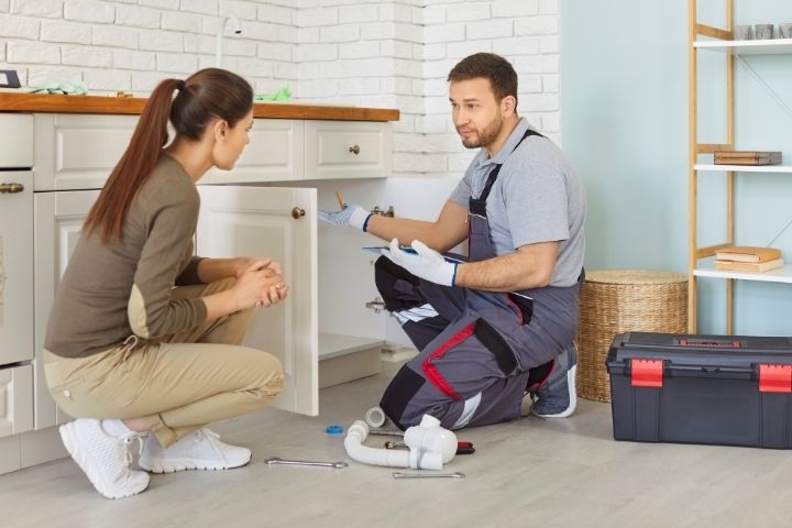 A technician discussing repair recommendations with a homeowner after a plumbing inspection.