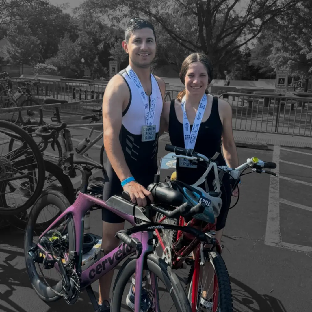 paul el zoghbi standing next to his wife after one of his triathlon races with his bike and equipment in hand