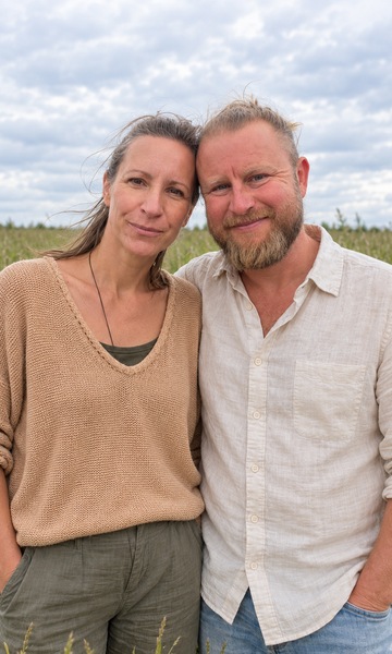 Mit KI bearbeitetes Bild nach Fotos von Andi und Katrin: beide stehen nebeneinander auf einer Wiese und schauen ruhig in die Kamera