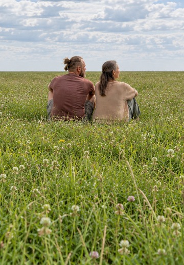 Mit KI bearbeitetes Bild nach Fotos von Andi und Katrin: beide sitzen still nebeneinander auf einer Wiese