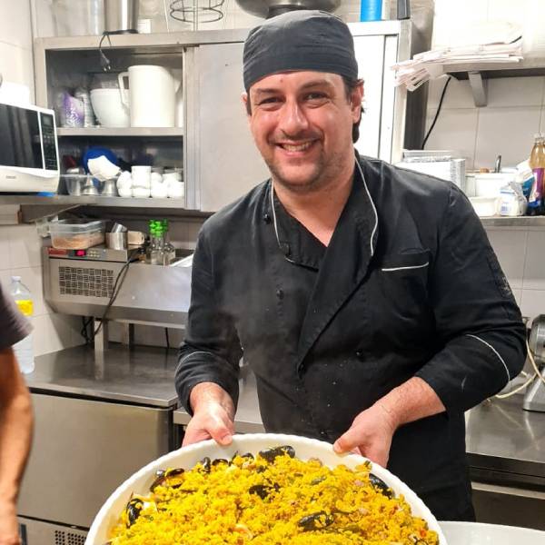 Chef ai fornelli con padella di paella