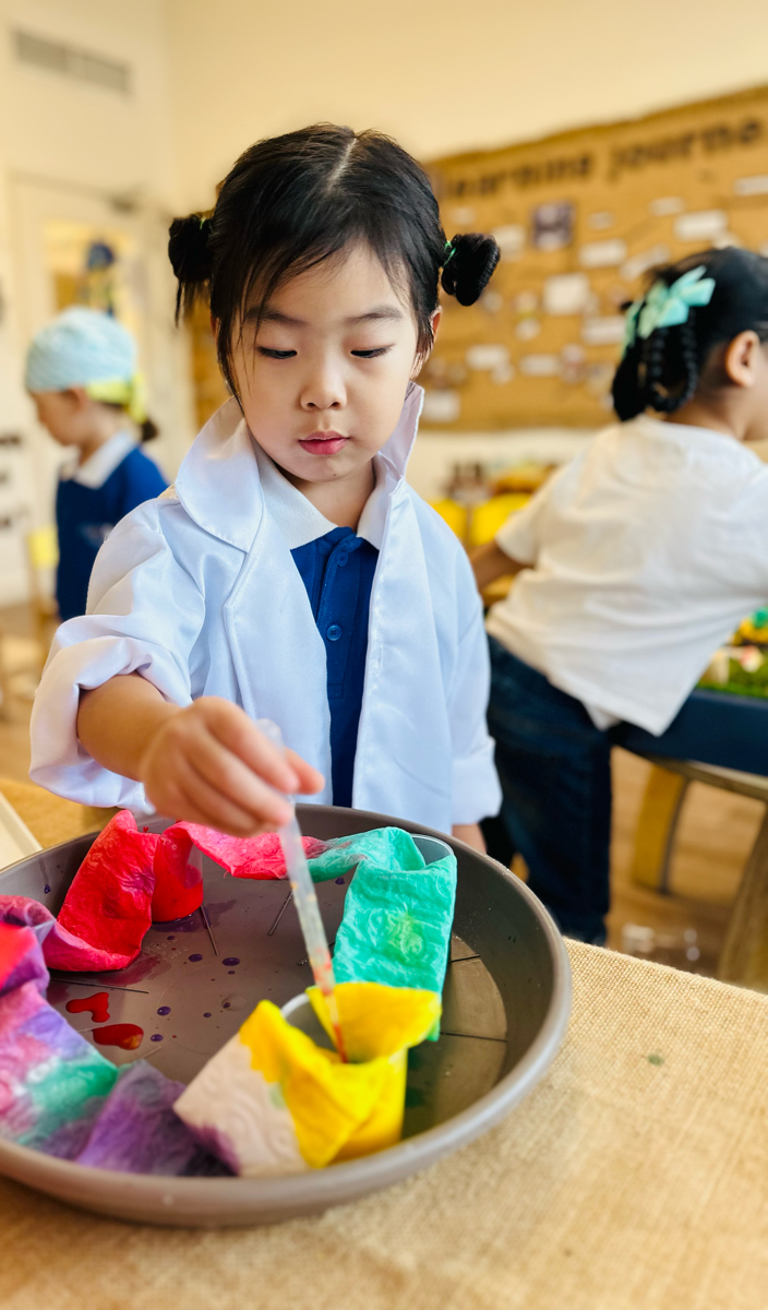 Child exploring colour and painting materials at Discovery Nursery, experimenting with paint and different textures during a creative activity