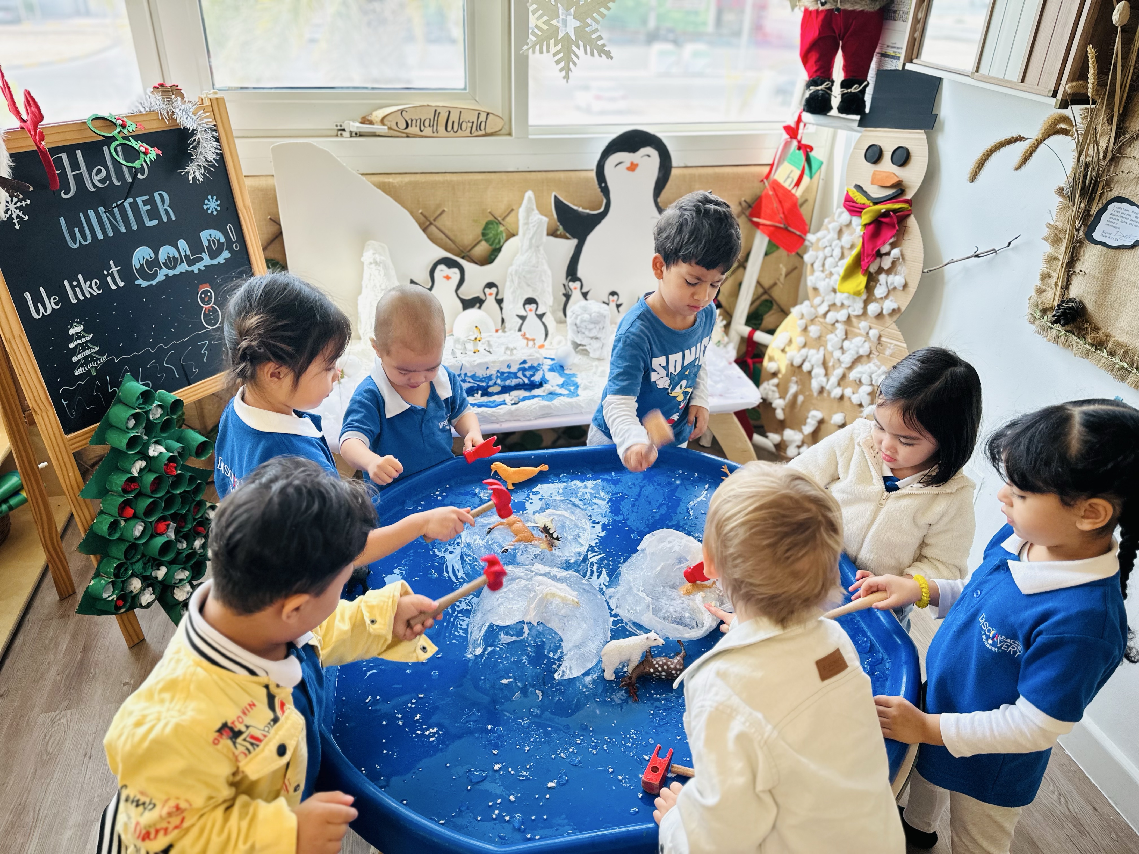 Children working together to investigate a winter-themed sensory activity with ice, water and small-world materials at Discovery Nursery