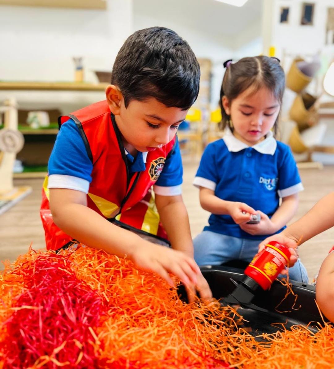 Children exploring an open-ended sensory activity at Discovery Nursery Abu Dhabi, using shredded paper and everyday materials to investigate texture, movement and creative possibilities