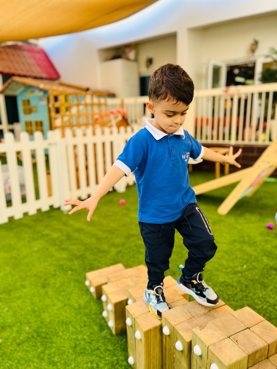 Child exploring balance and movement on a wooden stepping course at Discovery Nursery, developing confidence and independence through active play
