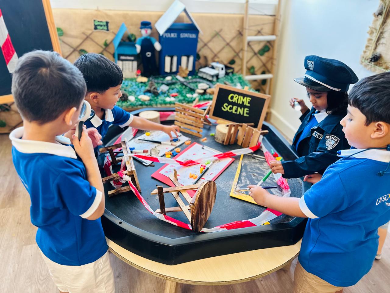 Children investigating a pretend crime scene through imaginative play and collaborative problem-solving at Discovery Nursery