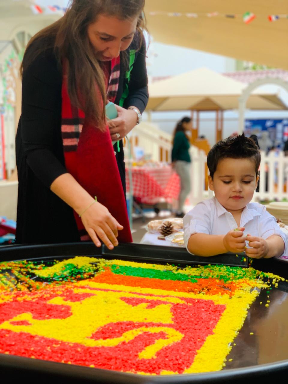 A child exploring a colourful sensory rice activity with his mum at Discovery Nursery, using hands-on materials to investigate textures and patterns