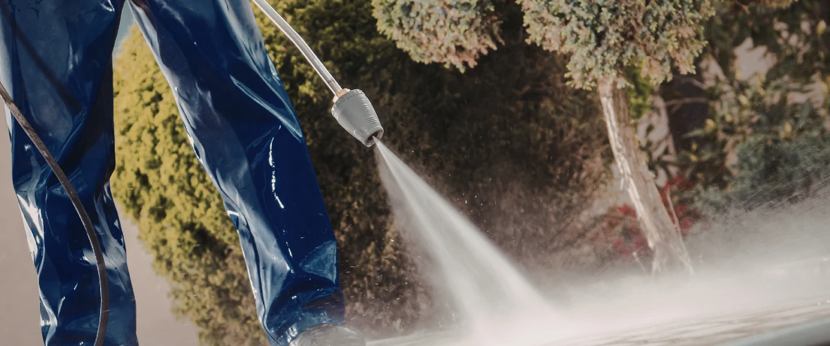 Close-up of a high-pressure water jet cleaning a driveway surface. Close-up of a high-pressure water jet cleaning a driveway surface.