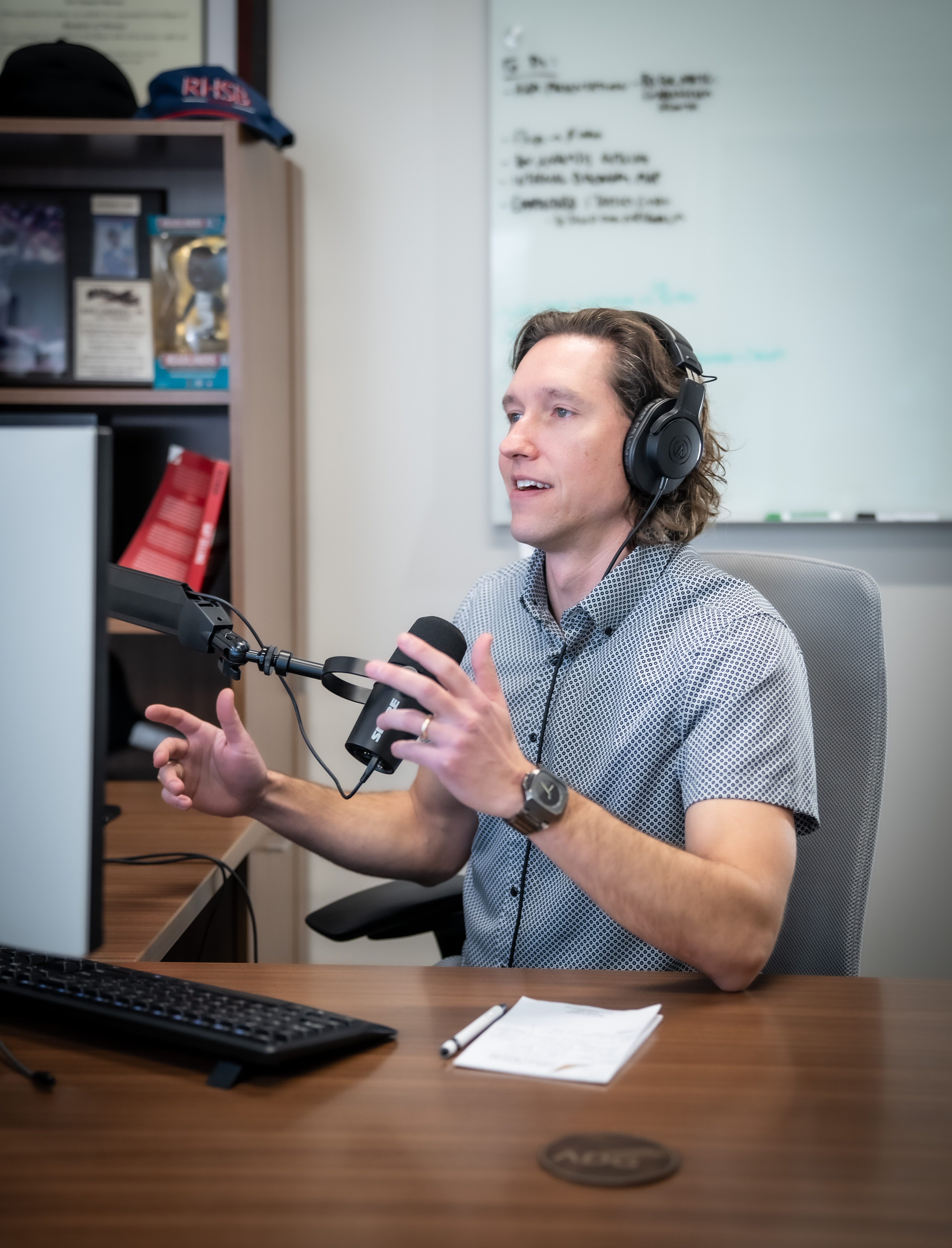 Neil Barrow gesturing with his hands while recording a podcast at his desk