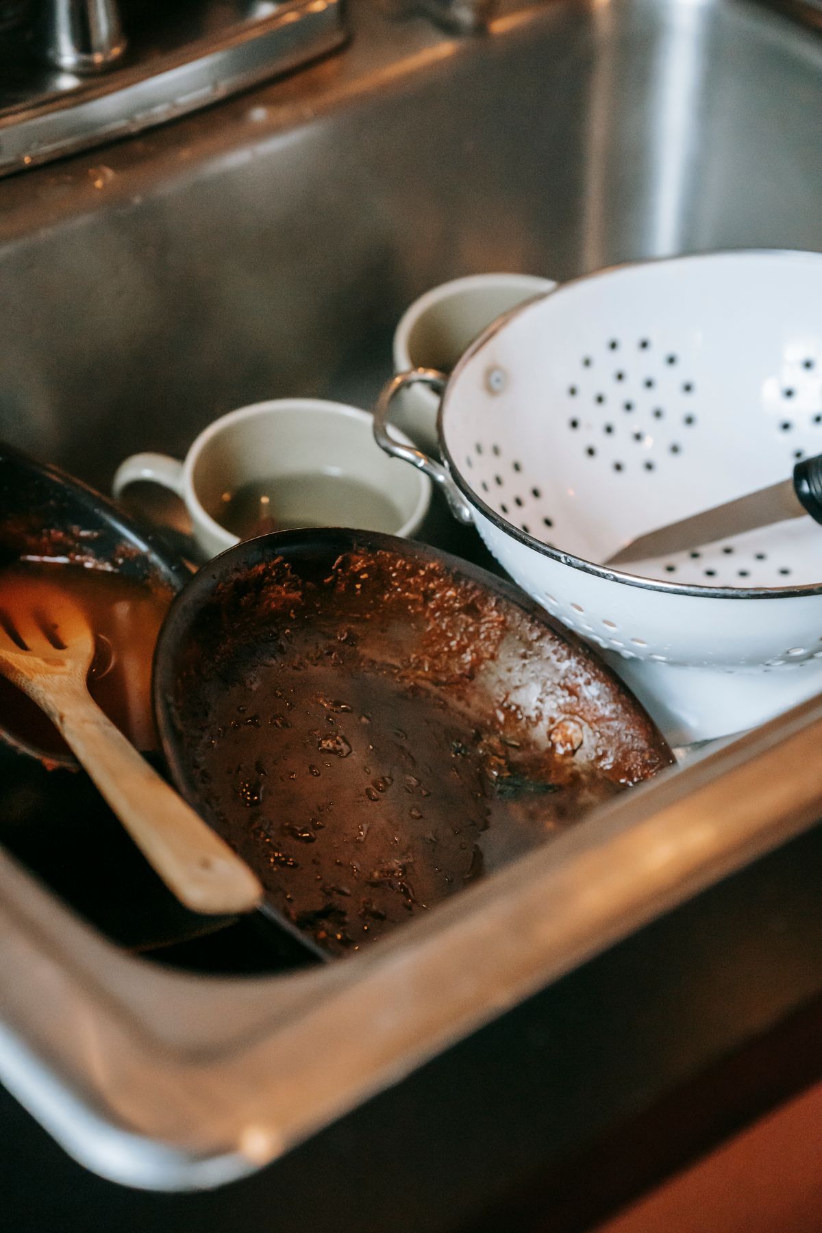 Dirty kitchen sink piled with dishes before cleaning