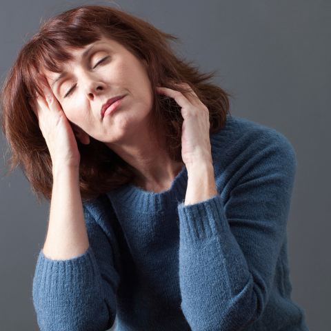 Woman reflecting on multiple health symptoms like fatigue and brain fog, trying to understand why she feels off