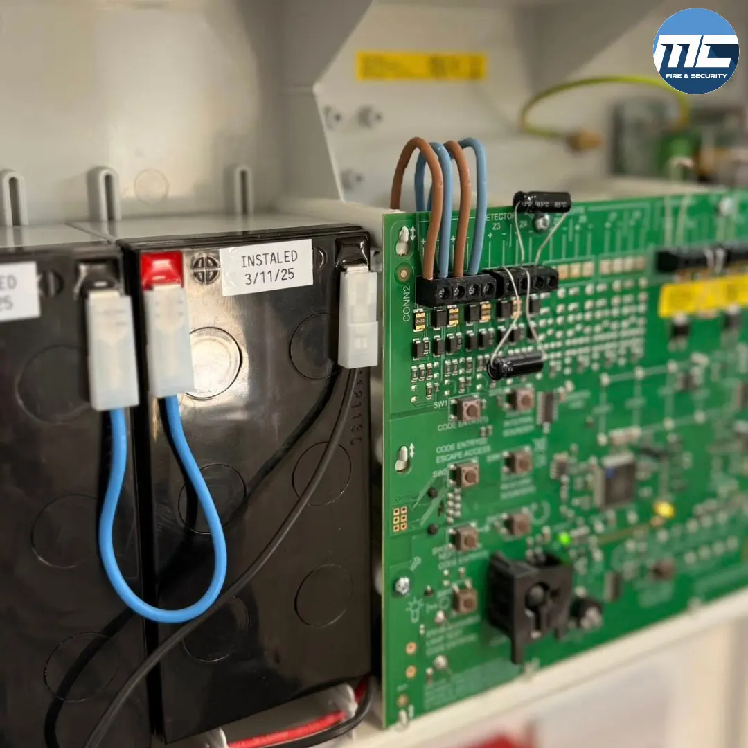 Inside a fire alarm panel — battery and circuit board during MC Fire & Security service