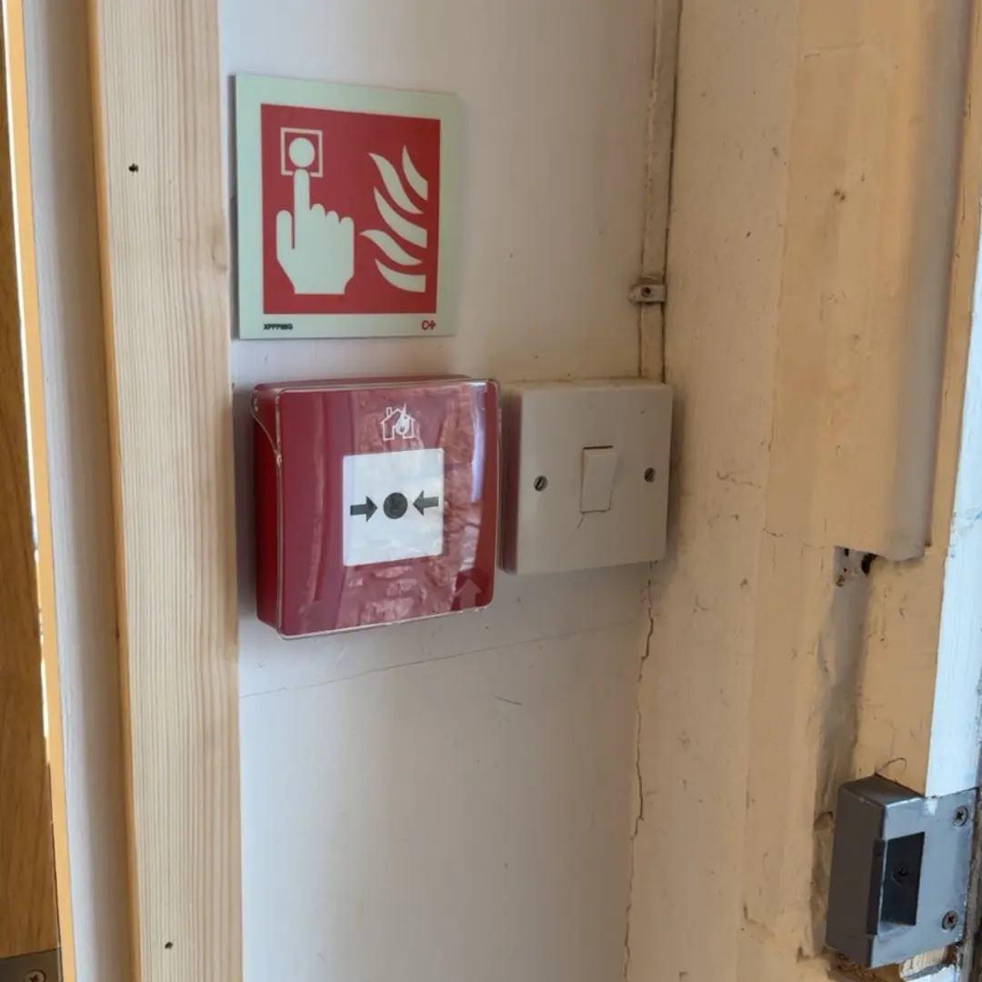Manual call point on stripped timber wall — wireless Ajax fire alarm install