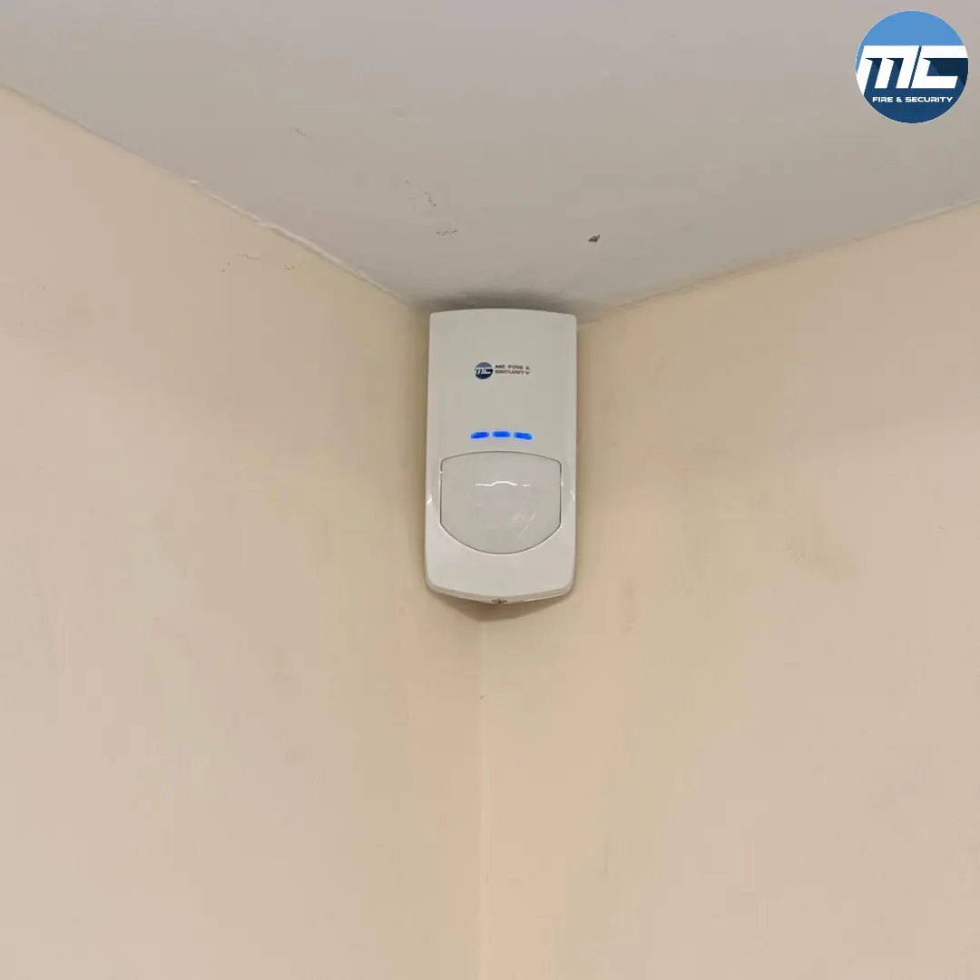 PIR motion detector wall-mounted in corner — intruder alarm install