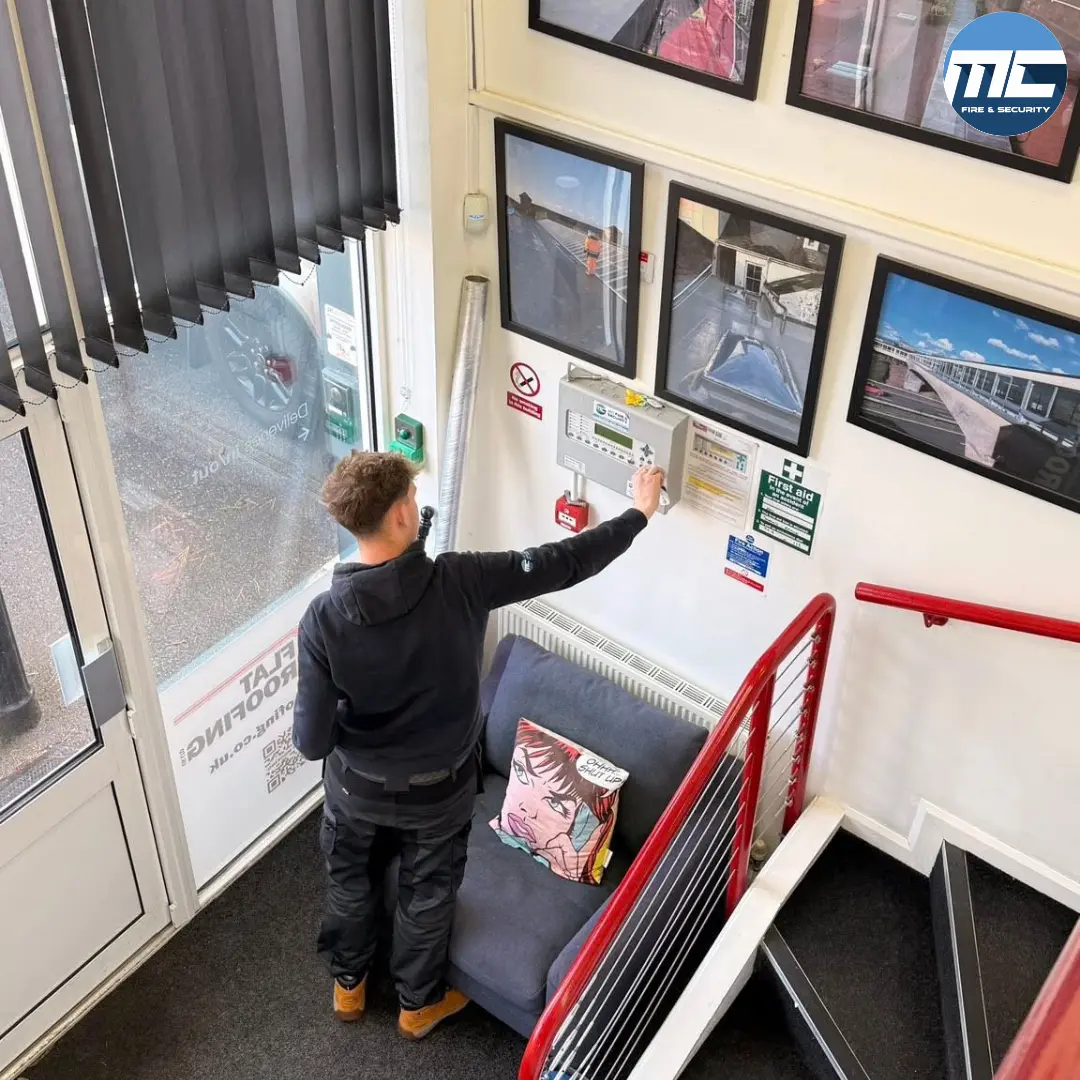 MC Fire & Security engineer working on fire alarm panel in stairwell