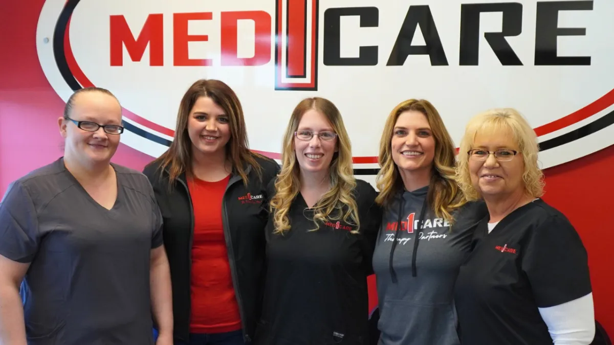 Med1Care team members in front of the company sign