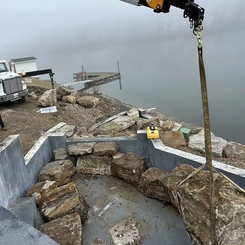 Parker knuckle-boom crane setting boulders along a shoreline rock wall