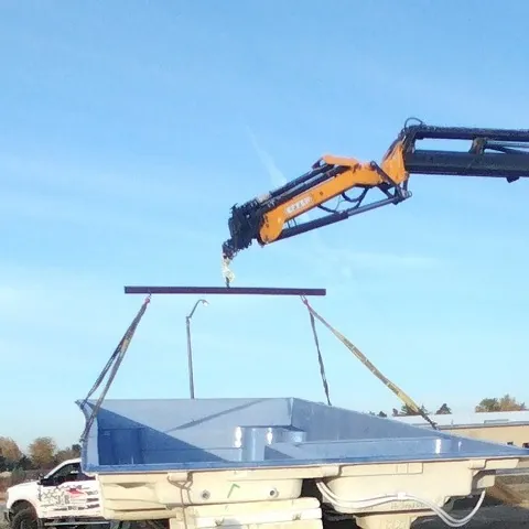 Parker knuckle-boom crane lifting a fiberglass pool shell on a spreader bar