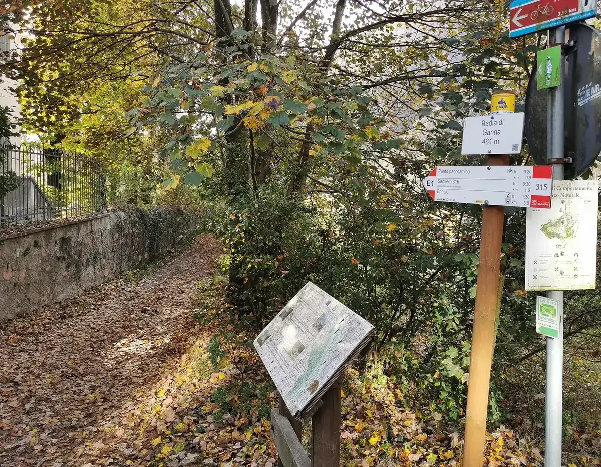Imbocco del sentiero presso la Badia di Ganna, con segnaletica escursionistica.