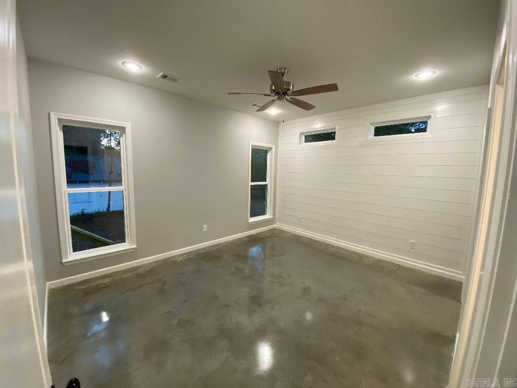 Primary bedroom with shiplap accent wall and concrete floors