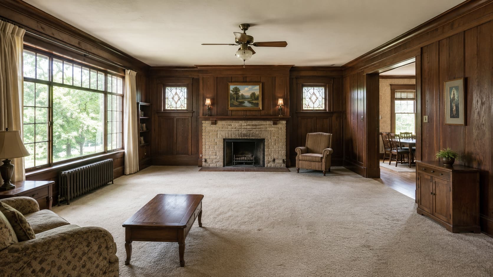 Spacious dated living room with wood paneling, large windows, fireplace, and strong renovation potential.