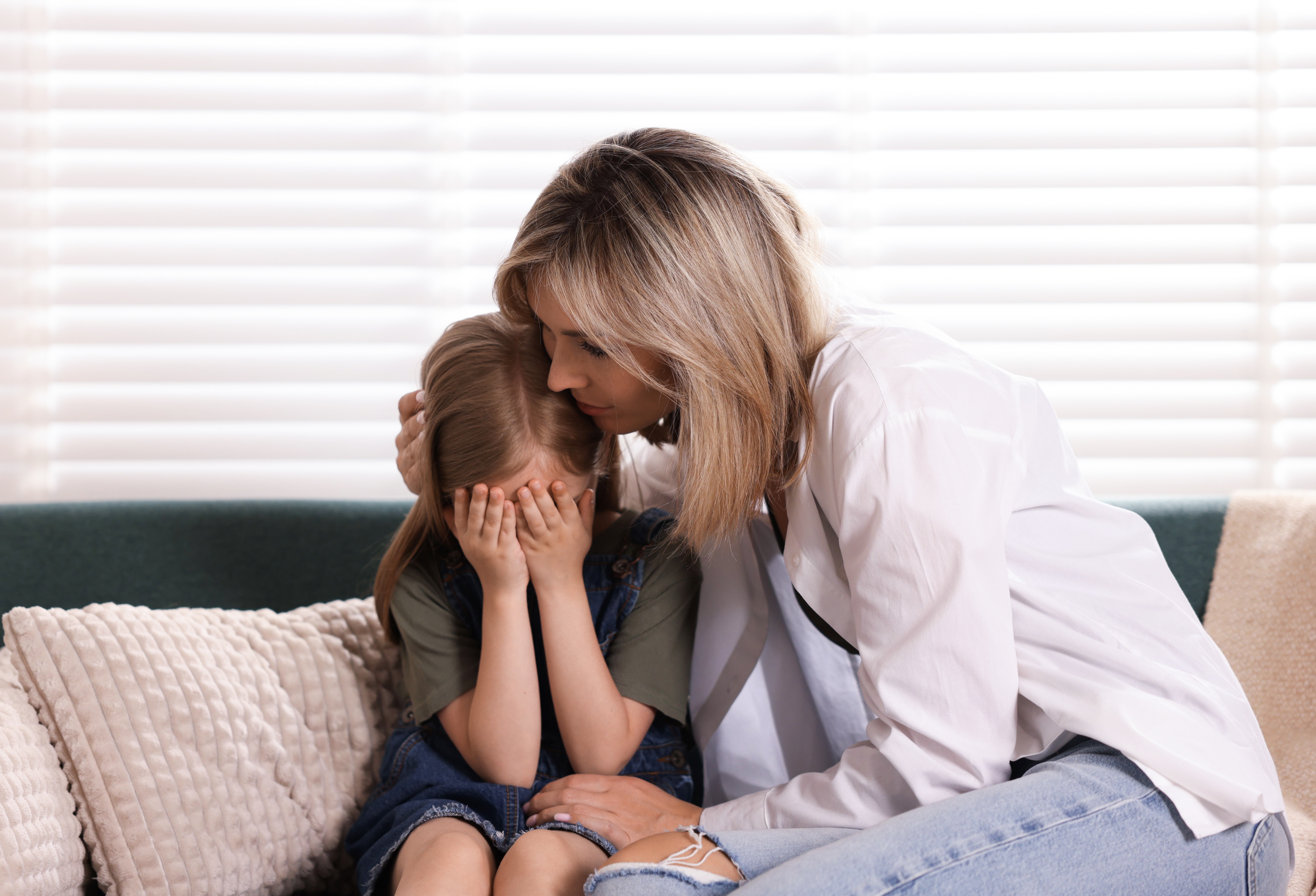 Mum comforting her daughter on the sofa