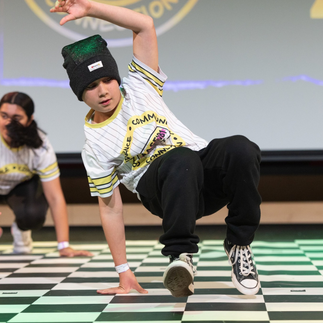 A girl in the middle of a cypher or freestyle dance session at Base 181 Studios, performing hip hop and jazz moves. She is being cheered on by her teammates with smiles, cheers, and claps of achievement. Fun and engaging kids dance classes.