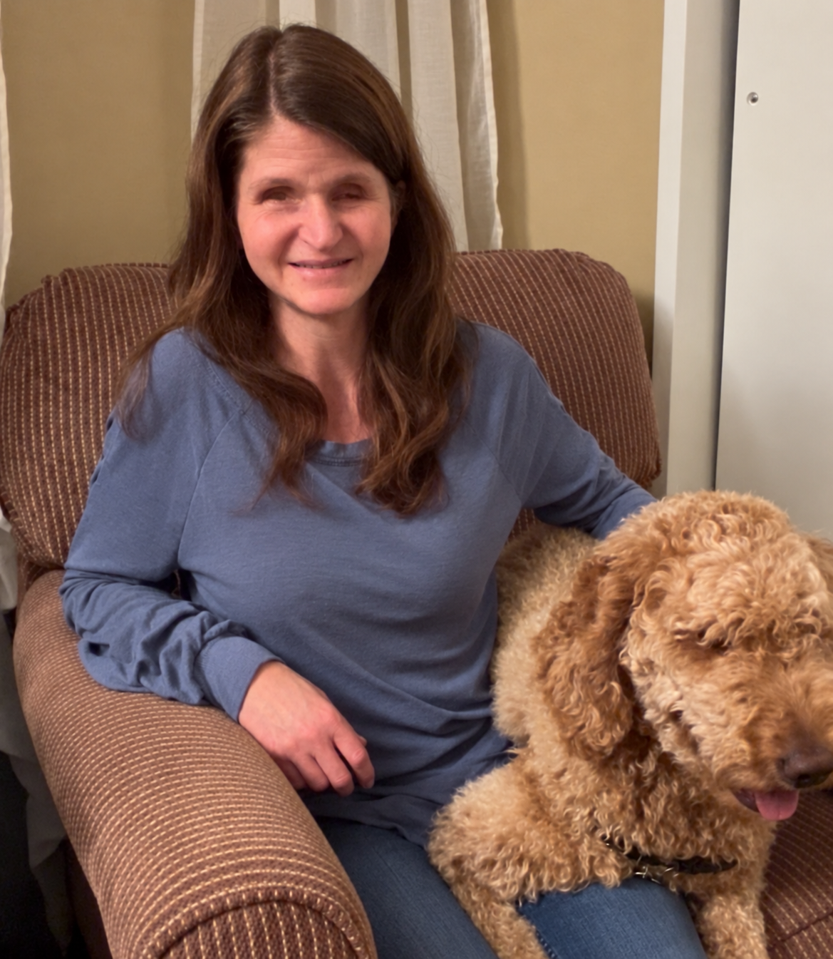 Jenna sitting in an armchair with her dog beside her.