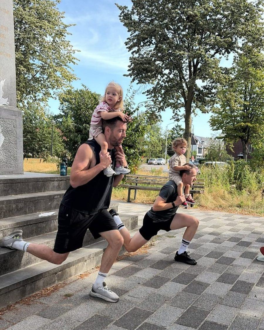 Twee vaders doen een split squat met hun kind op de schouders