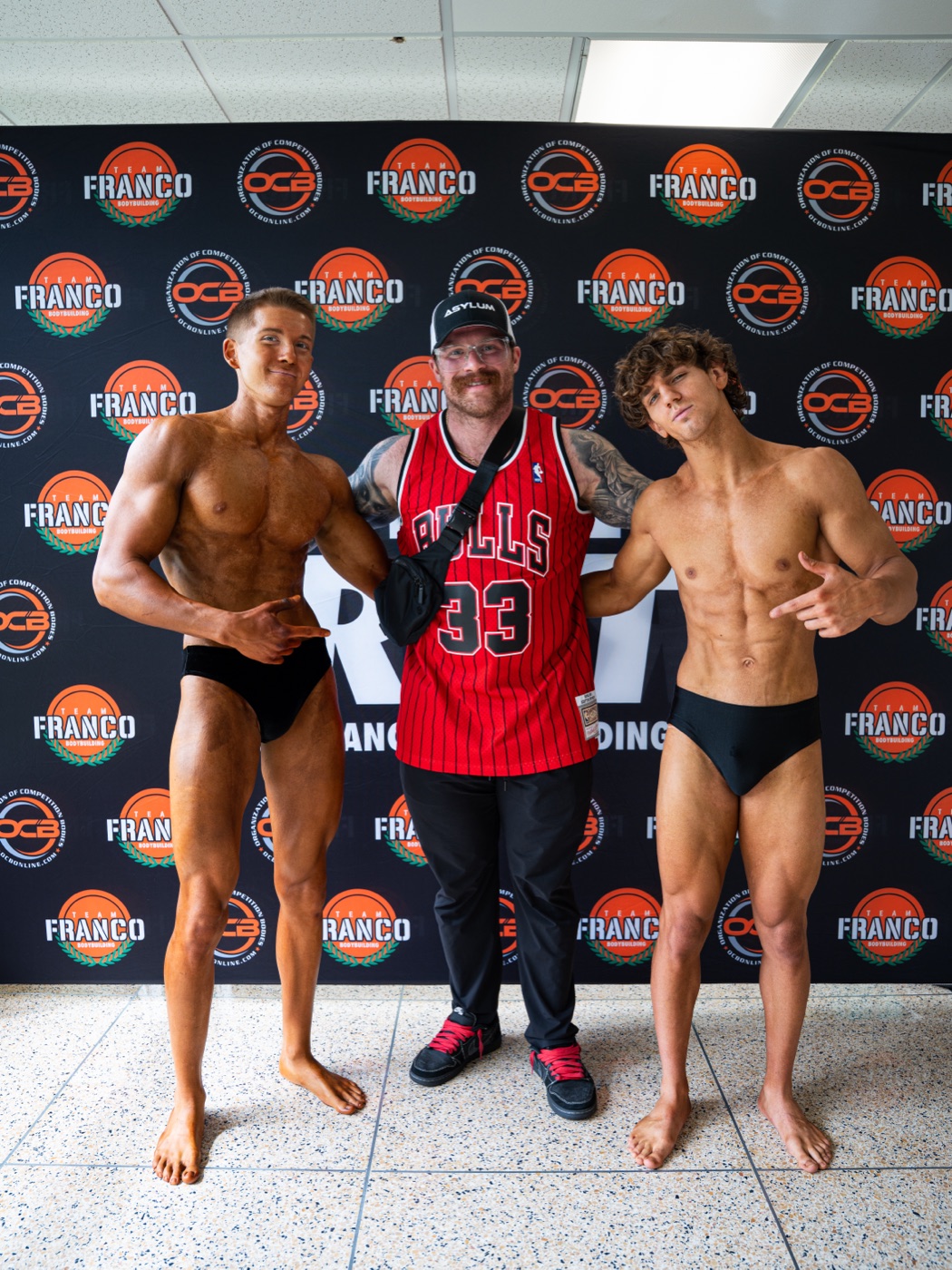 Asylum coach backstage with two physique competitors