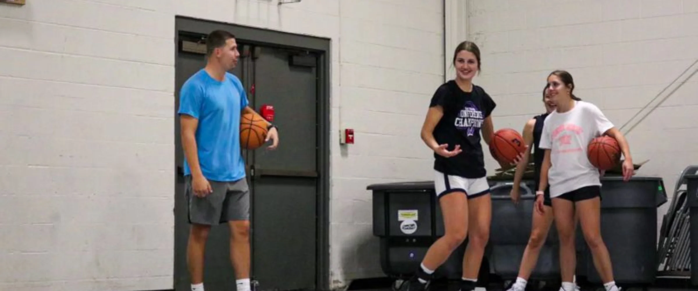 Three young basketball players, a male and two females, stand in a gym holding basketballs. Three young basketball players, a male and two females, stand in a gym holding basketballs.