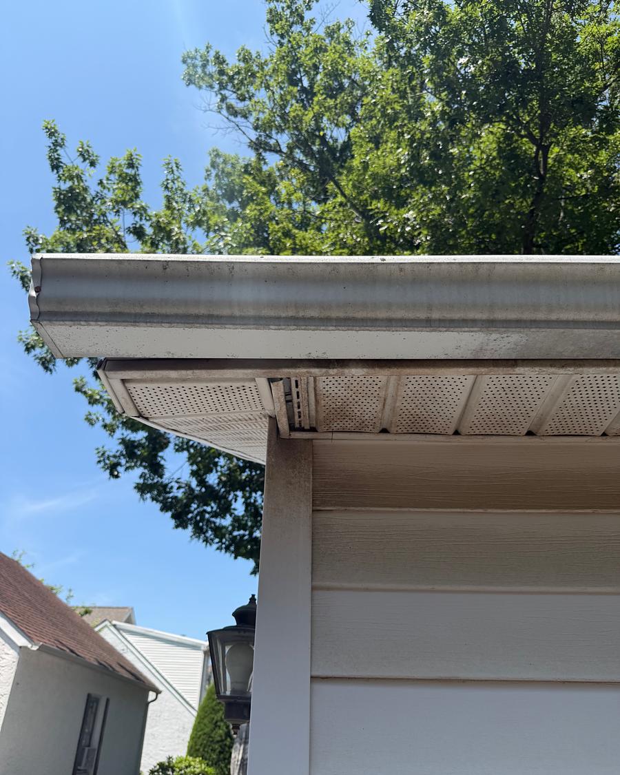 Clean white gutter run and soffit against a blue sky after gutter brightening
