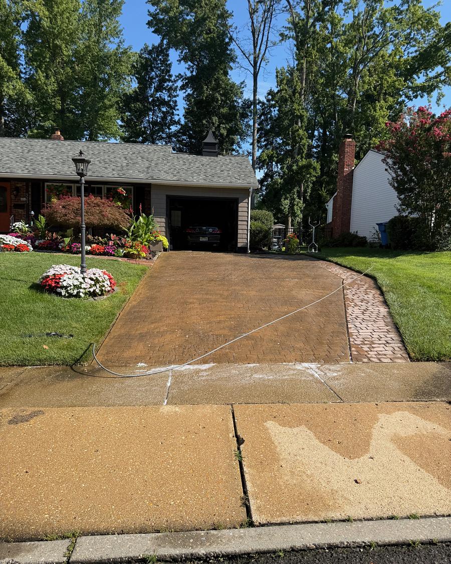 Washed stamped concrete driveway in Cherry Hill, NJ with a clean paver border and planted bed