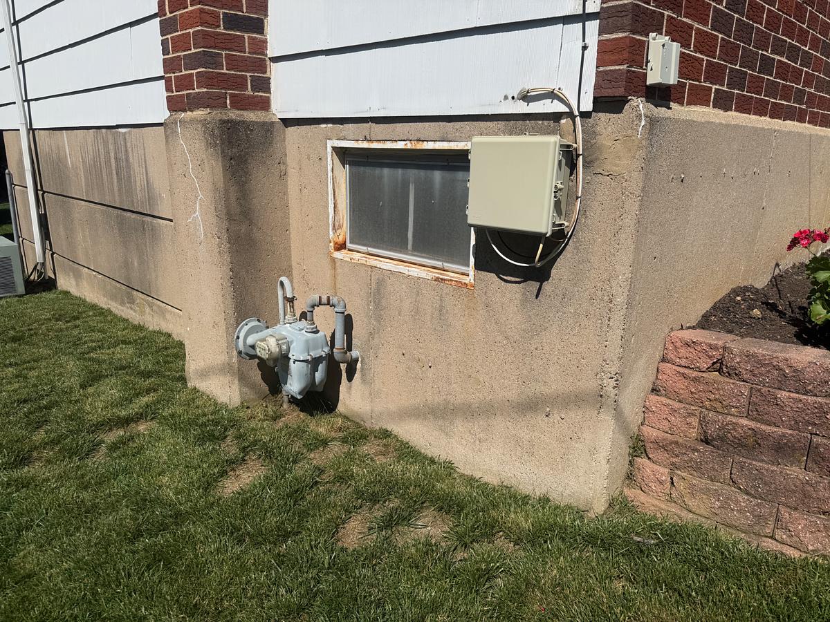 Painted concrete house foundation streaked and darkened with algae and dirt before washing