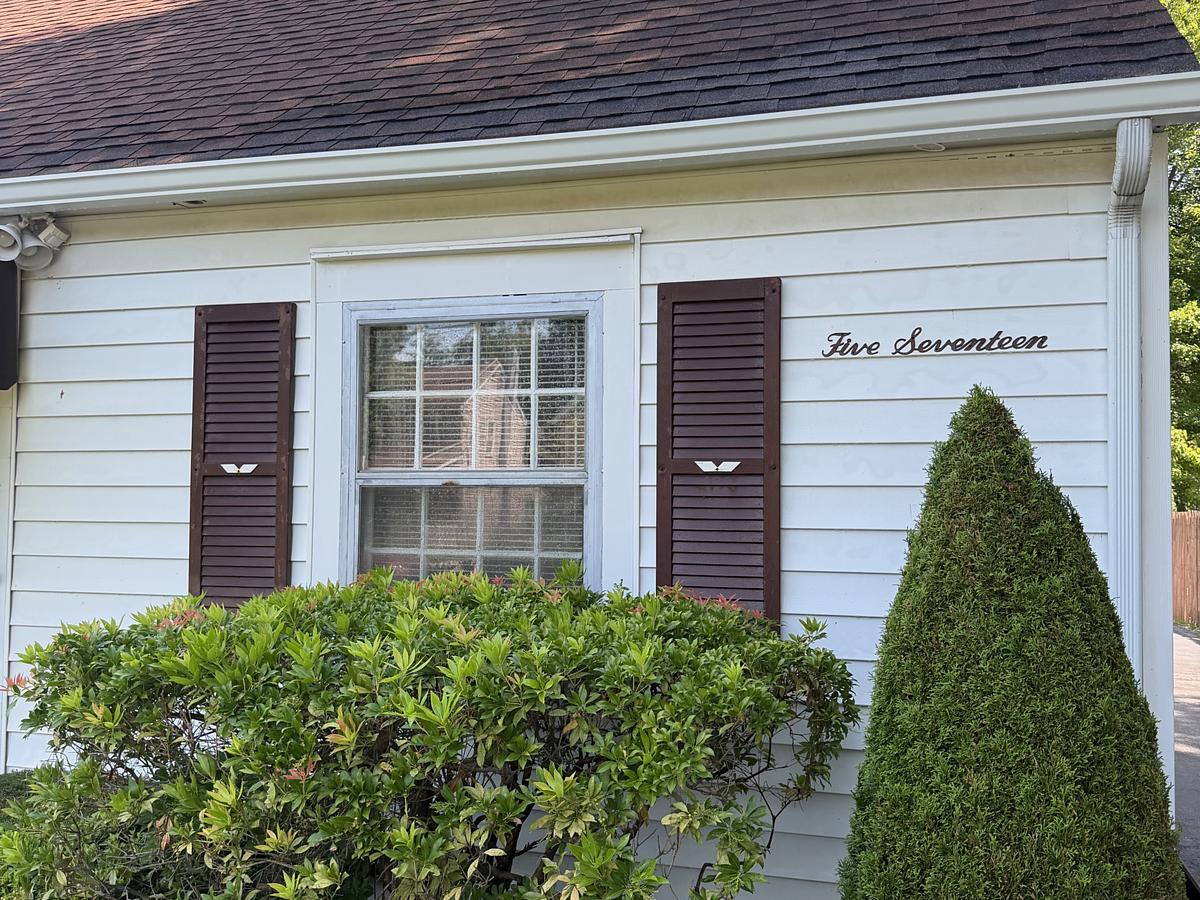White clapboard cape with brown shutters in Havertown, PA after a house wash and gutter brightening