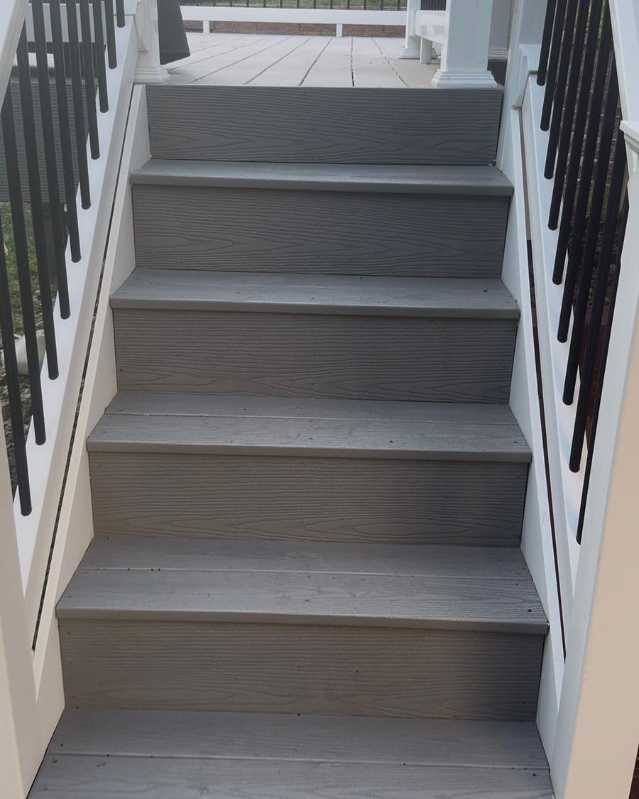 Composite deck stairs washed clean, with white risers and a black metal rail