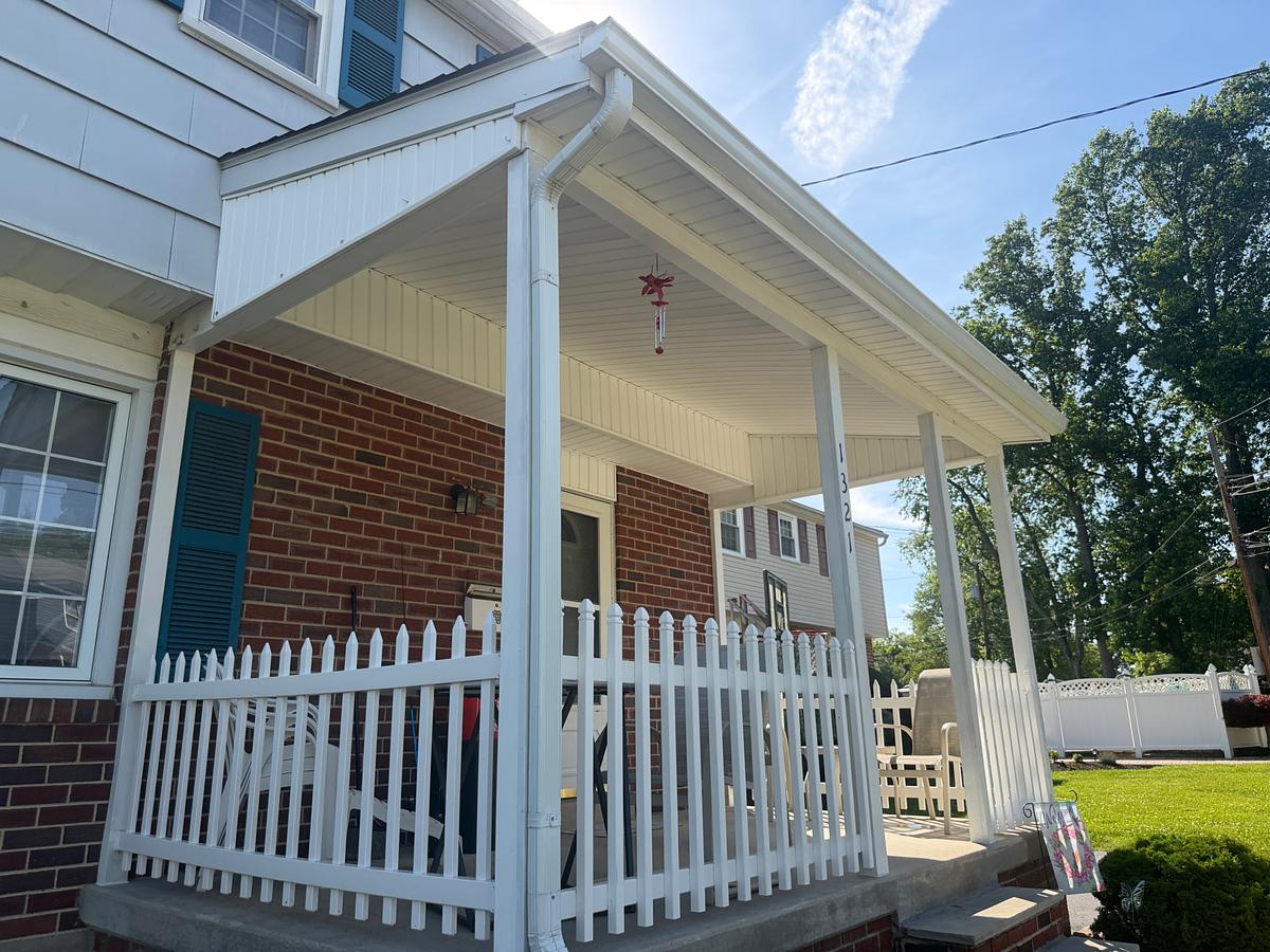 Clean white covered front porch with picket railing on a brick Havertown, PA home after washing