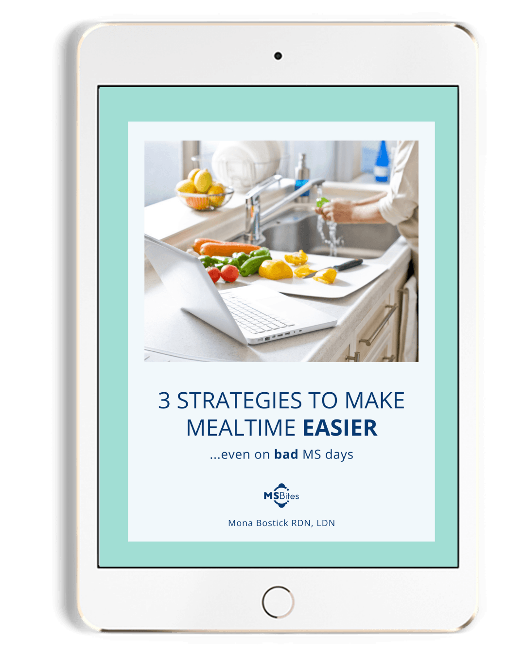 A laptop sits on a kitchen counter next to fresh vegetables and a bowl of fruit, with text that reads "3 Strategies to Make Mealtime Easier... Even on Bad MS Days".