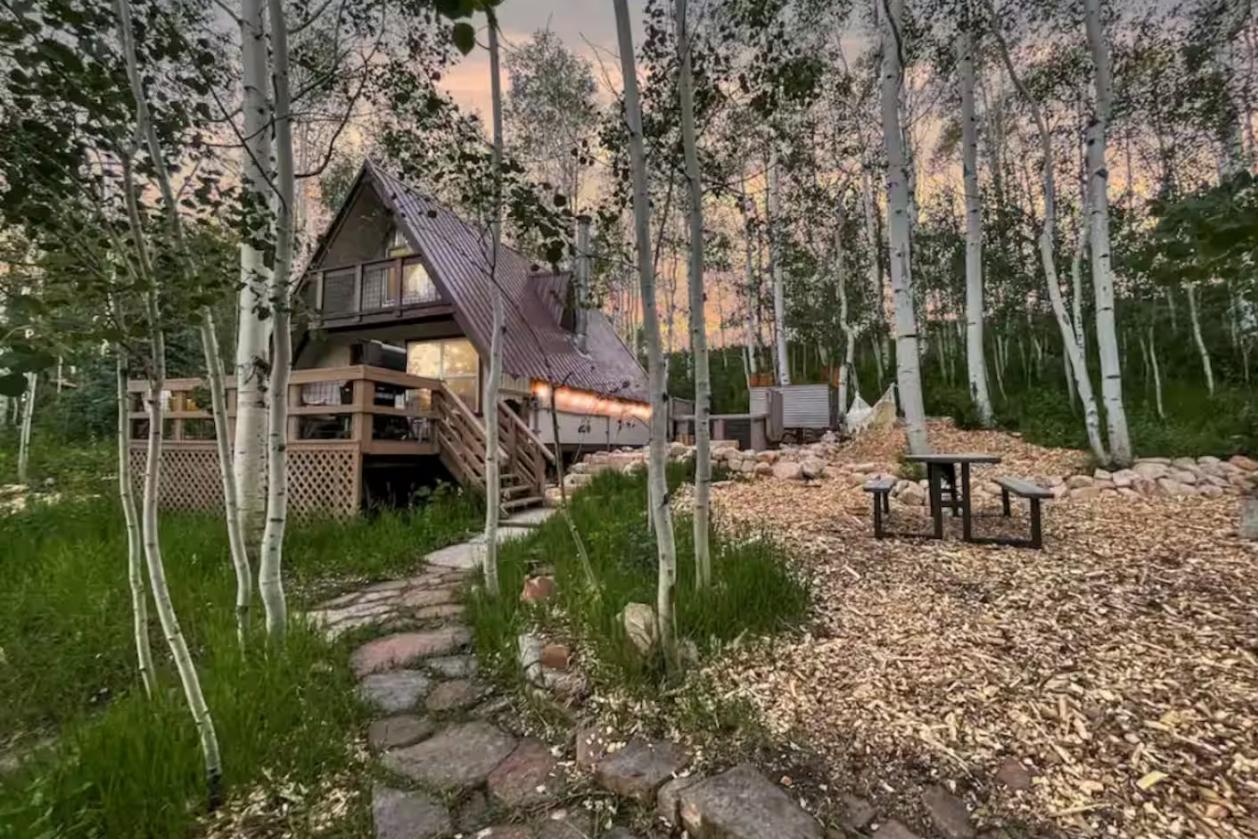 An A-frame cabin among aspens at dusk