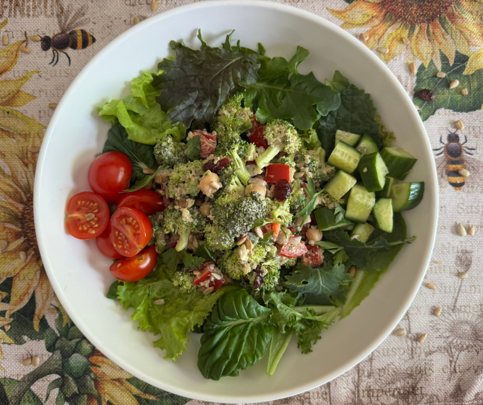 Broccoli quinoa salad served over leafy greens with tomatoes and cucumber