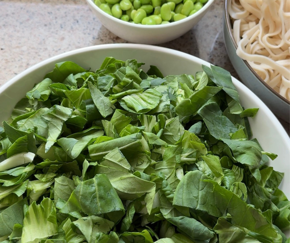 Chopped pac choi prepared for a meal with edamame and noodles