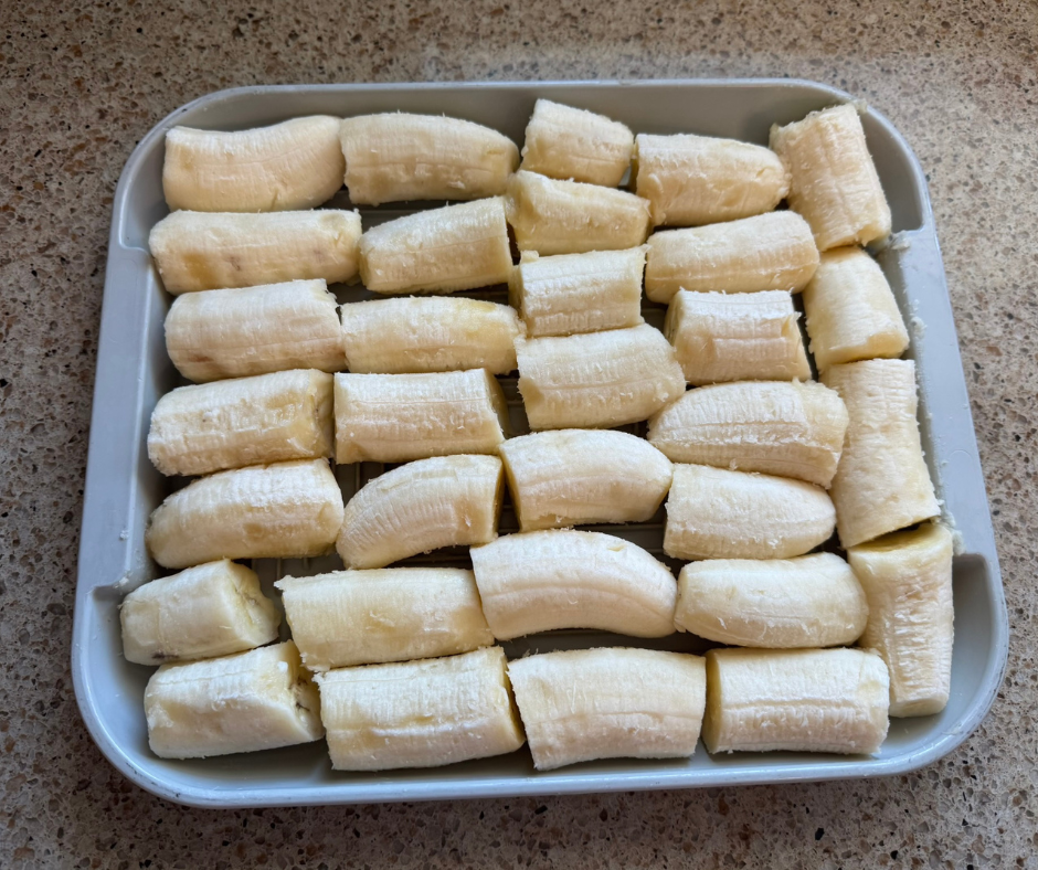 Ripe banana chunks arranged on a tray for freezing